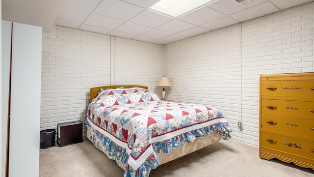 carpeted bedroom featuring a paneled ceiling and brick wall