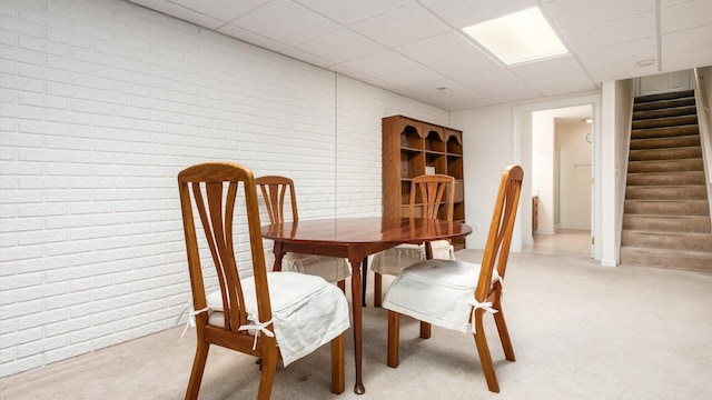 dining room with a drop ceiling, light colored carpet, and stairway