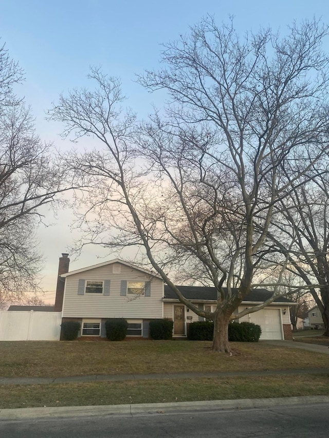 tri-level home featuring a garage and a lawn