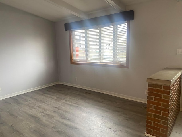 empty room with beam ceiling and hardwood / wood-style flooring