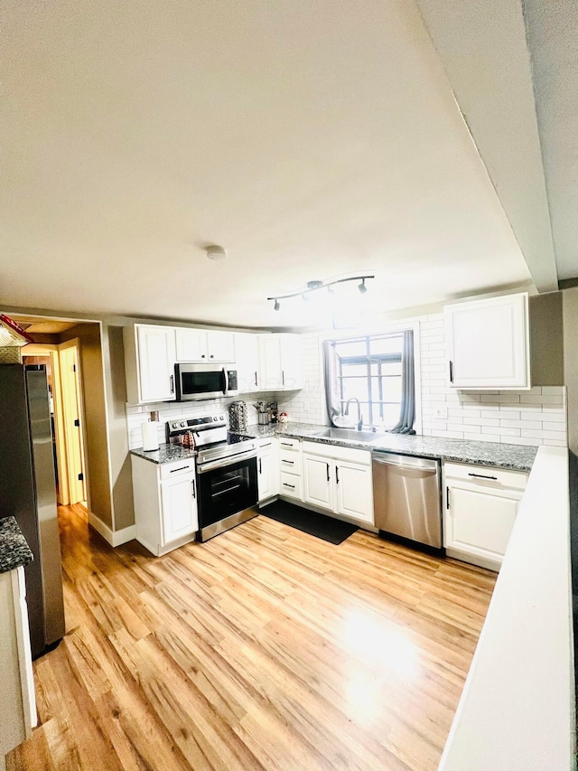 kitchen featuring tasteful backsplash, white cabinetry, appliances with stainless steel finishes, and light wood-type flooring