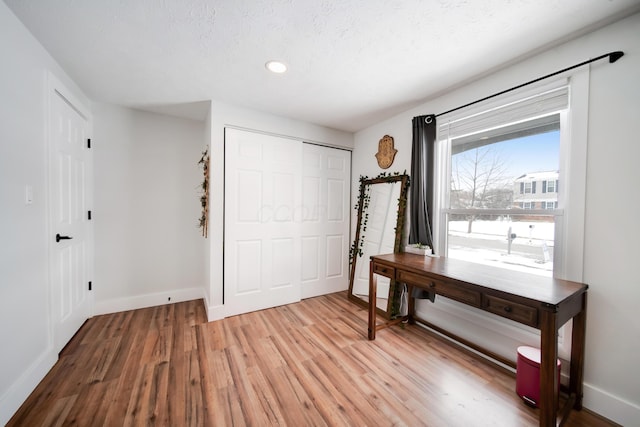 foyer with a textured ceiling, light wood-type flooring, and baseboards