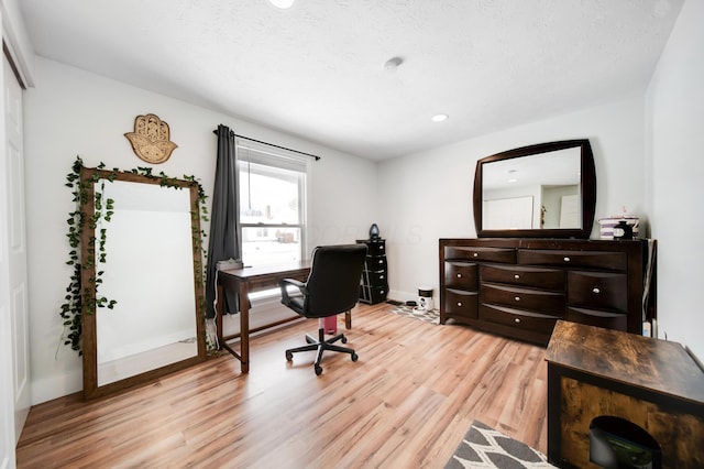 office featuring light wood-style flooring, baseboards, and a textured ceiling