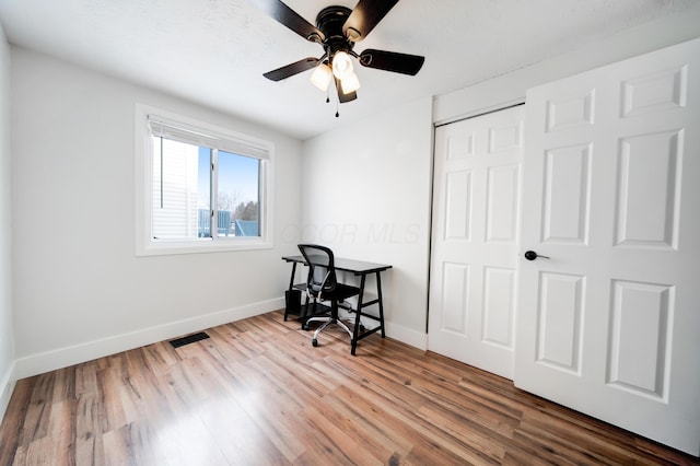 home office with a ceiling fan, visible vents, baseboards, and wood finished floors