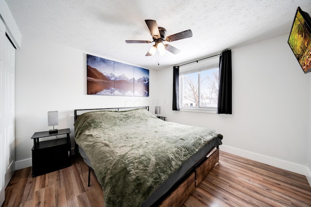 bedroom featuring a textured ceiling, baseboards, and wood finished floors