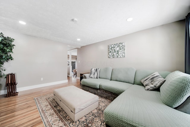 living room with light wood-style flooring, baseboards, a textured ceiling, and recessed lighting