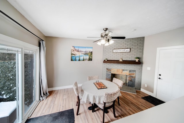 dining area with a brick fireplace, baseboards, and wood finished floors