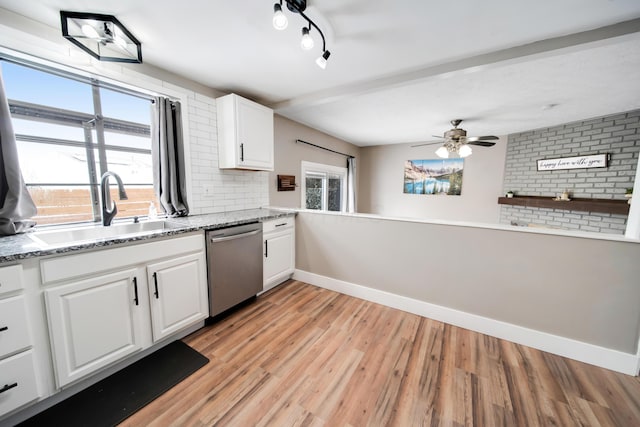 kitchen featuring tasteful backsplash, white cabinets, light wood-type flooring, stainless steel dishwasher, and a sink