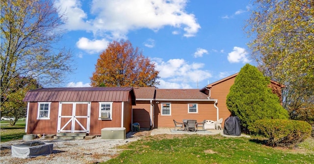 back of property with a yard, a patio area, and a shed