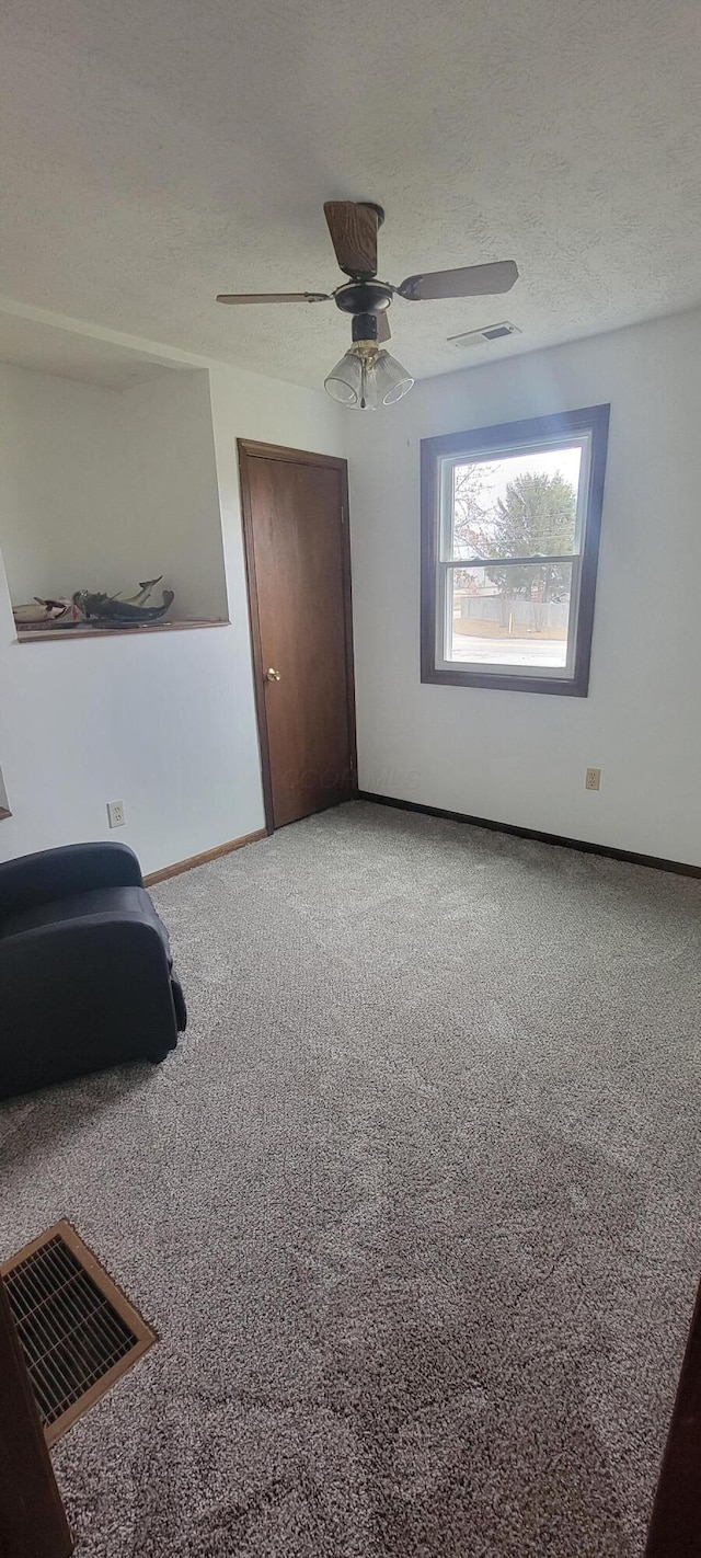 interior space featuring ceiling fan, carpet floors, and a textured ceiling