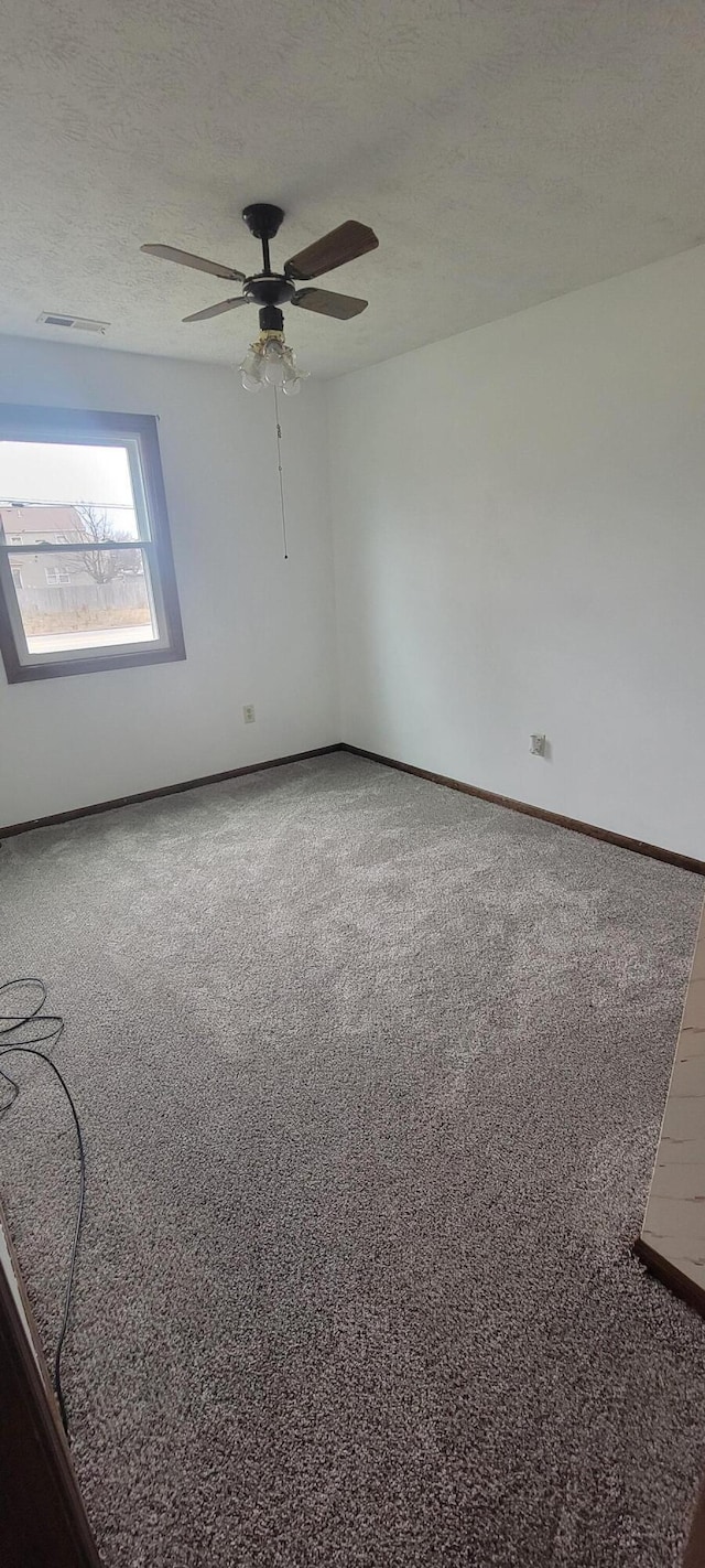 empty room with ceiling fan, carpet, and a textured ceiling