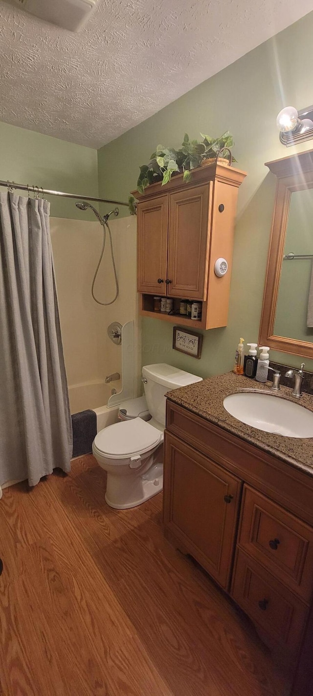 full bathroom with hardwood / wood-style flooring, vanity, toilet, a textured ceiling, and shower / bath combo with shower curtain