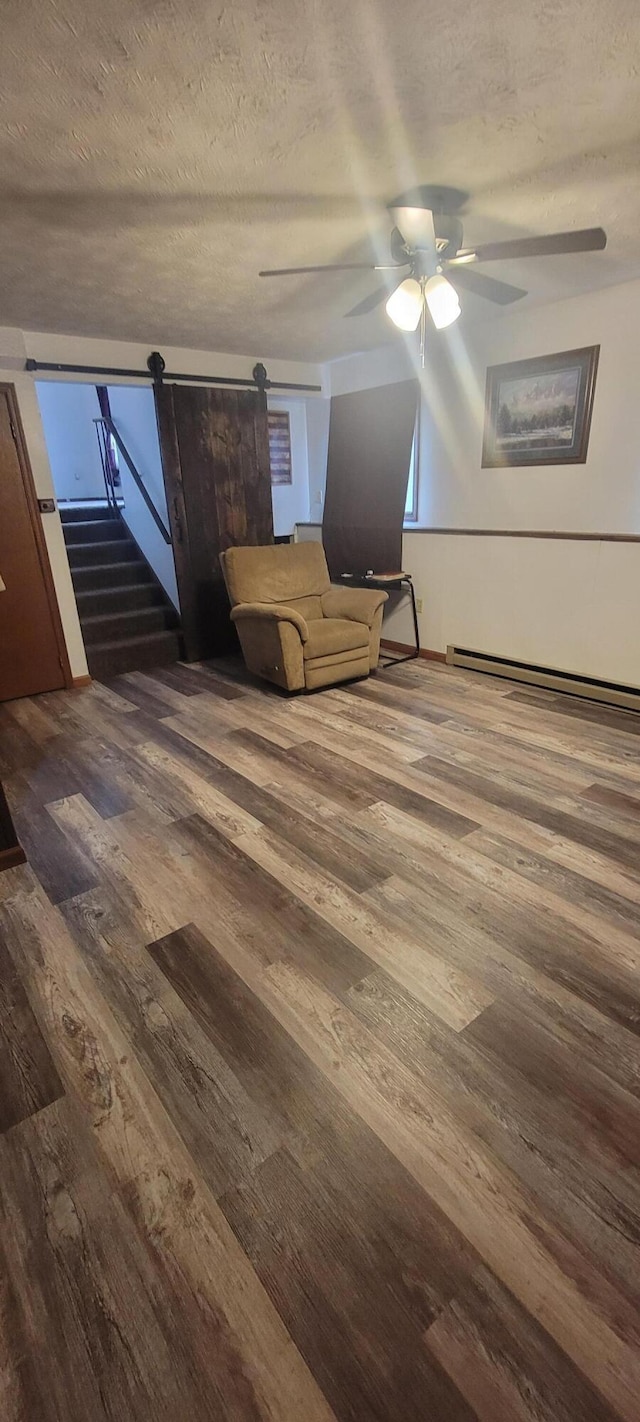 interior space with hardwood / wood-style floors, a baseboard radiator, a barn door, and a textured ceiling