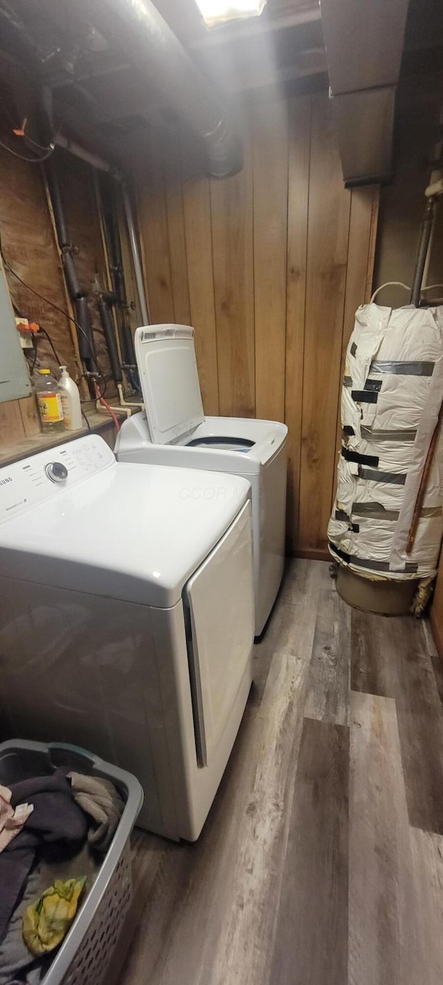 washroom featuring dark hardwood / wood-style floors, washing machine and dryer, and wood walls