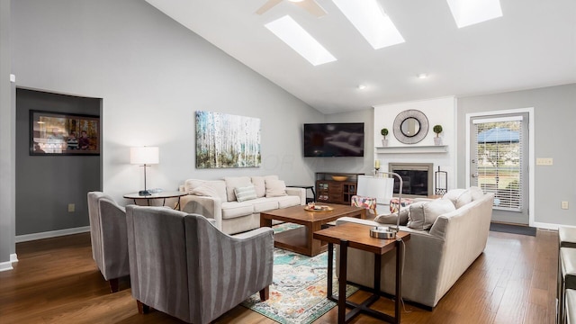 living room featuring a large fireplace, high vaulted ceiling, a skylight, and hardwood / wood-style floors