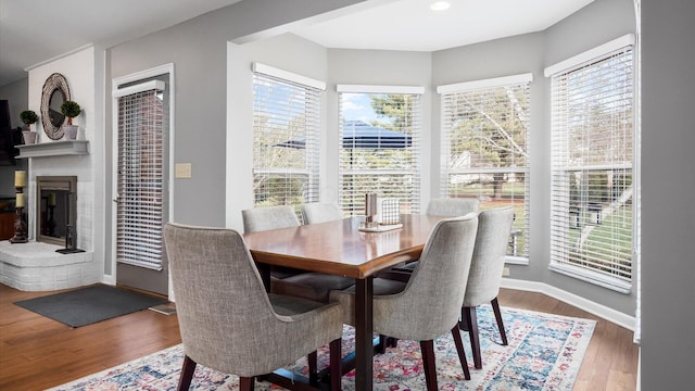 dining space with a healthy amount of sunlight, hardwood / wood-style floors, and a fireplace