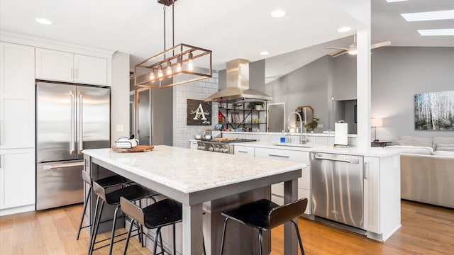 kitchen with white cabinetry, appliances with stainless steel finishes, sink, and island range hood