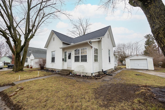 bungalow-style home featuring a garage, an outdoor structure, and a front lawn