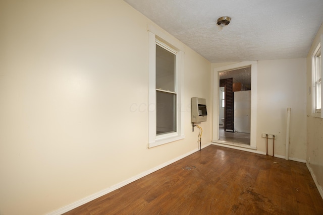 hall featuring hardwood / wood-style flooring, heating unit, and a textured ceiling