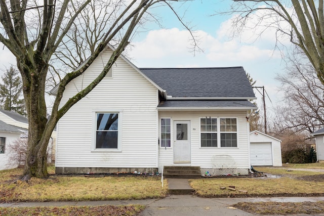 bungalow-style house with a garage, an outdoor structure, and a front lawn