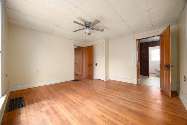 spare room with ceiling fan, a drop ceiling, and light wood-type flooring