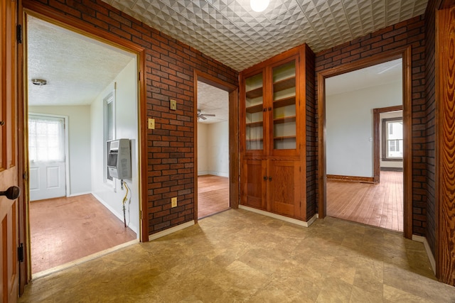 interior space featuring multiple windows, brick wall, light wood-type flooring, and a textured ceiling