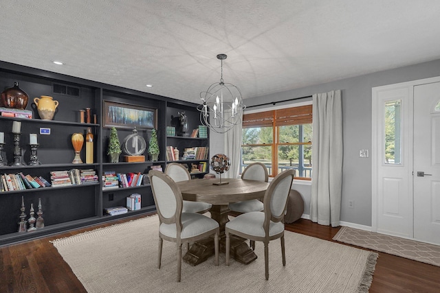 dining space with a chandelier, a textured ceiling, built in shelves, wood finished floors, and visible vents