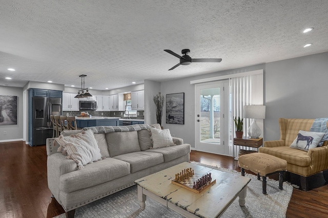 living room with ceiling fan, a textured ceiling, recessed lighting, baseboards, and dark wood finished floors