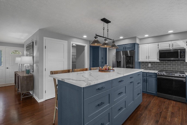 kitchen featuring dark wood-style floors, pendant lighting, tasteful backsplash, appliances with stainless steel finishes, and light stone countertops