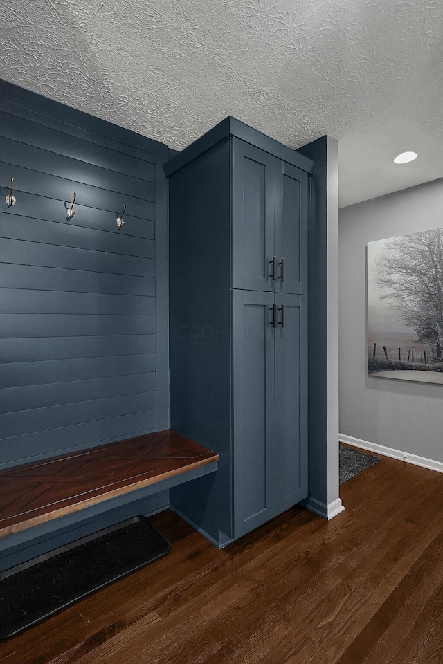 mudroom with dark wood-style flooring, a textured ceiling, and baseboards