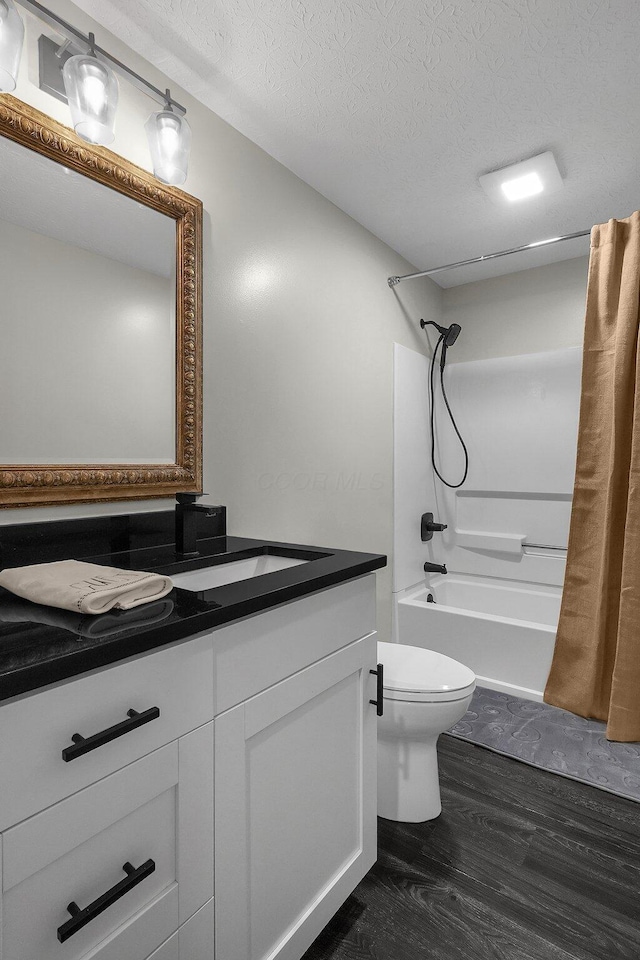 bathroom featuring shower / bathtub combination with curtain, toilet, vanity, a textured ceiling, and wood finished floors