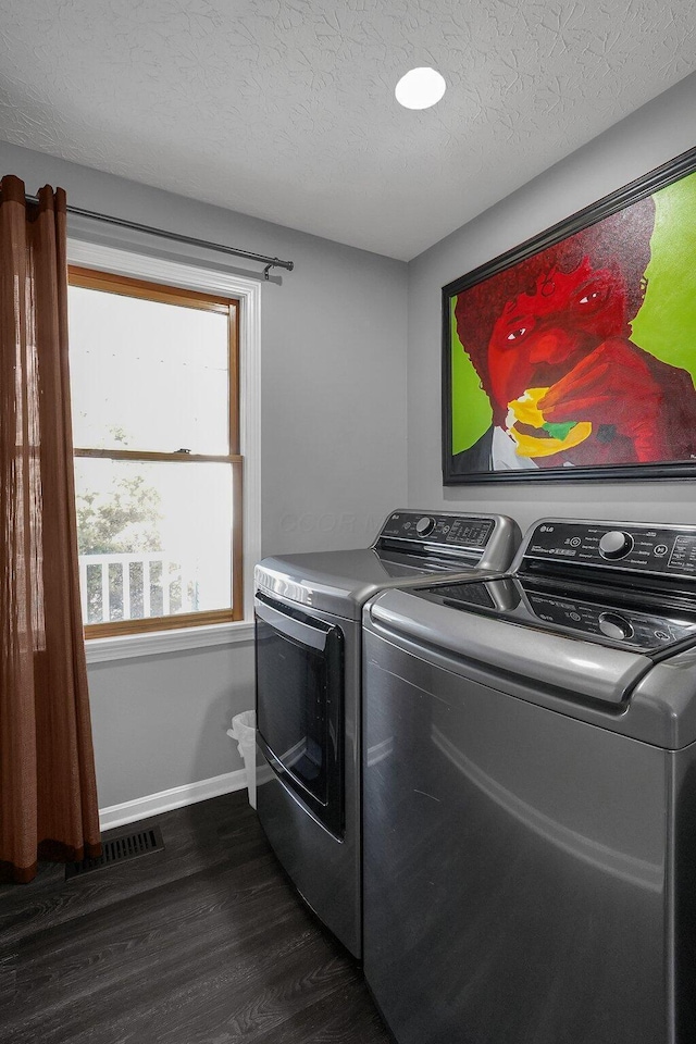 clothes washing area featuring dark wood-style flooring, washing machine and clothes dryer, visible vents, a textured ceiling, and laundry area