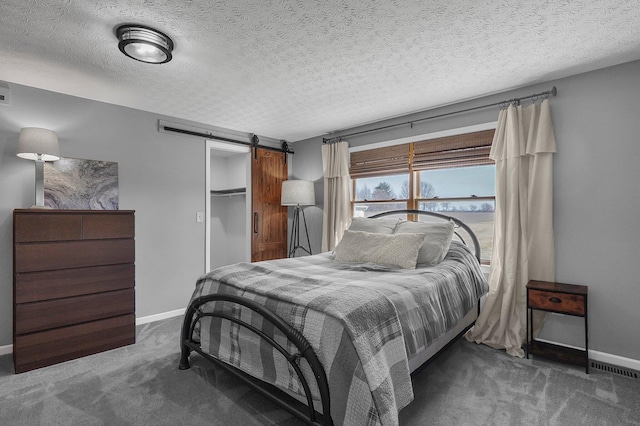 bedroom with carpet, a barn door, baseboards, and a textured ceiling