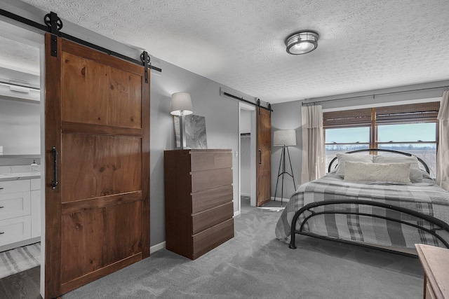 bedroom featuring light carpet, a textured ceiling, baseboards, and a barn door