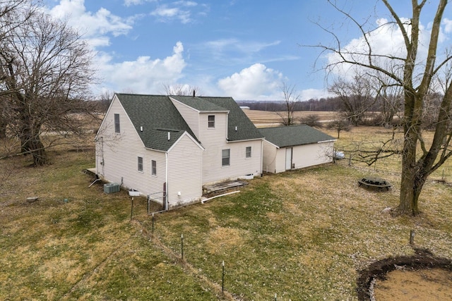 rear view of house with central AC and a lawn