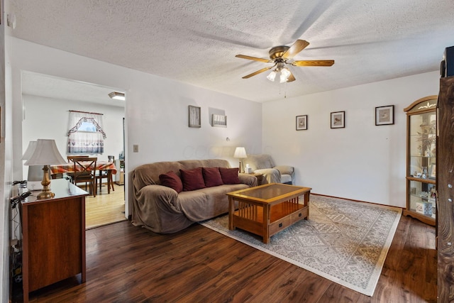 living room featuring dark hardwood / wood-style floors, a textured ceiling, and ceiling fan