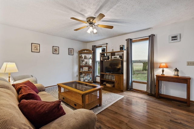 living room featuring ceiling fan, dark wood-type flooring, and a textured ceiling