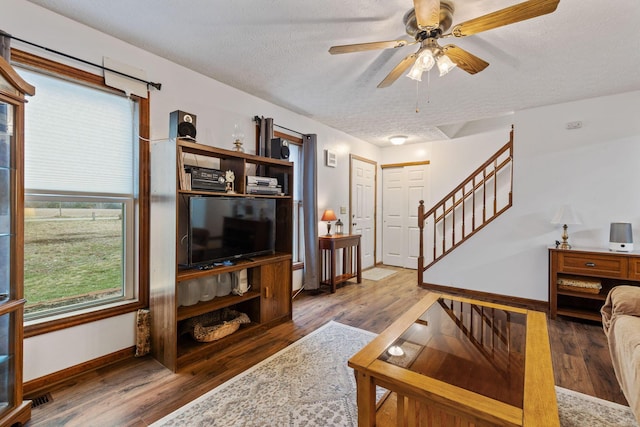 living room with ceiling fan, dark hardwood / wood-style floors, and a textured ceiling