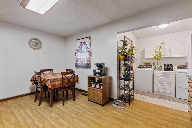 dining area featuring separate washer and dryer, a textured ceiling, and light wood-type flooring