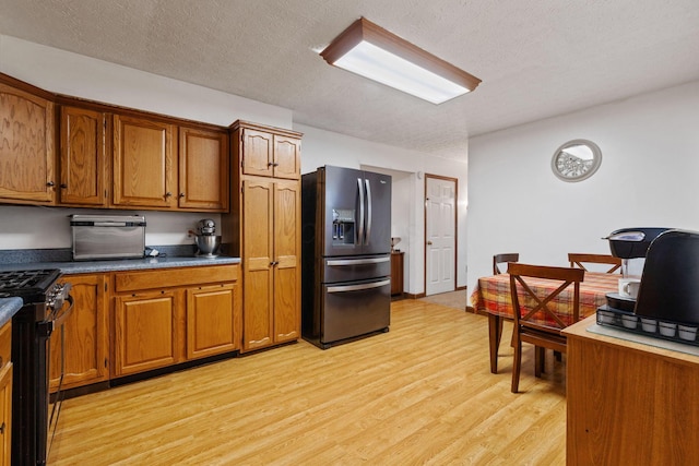 kitchen featuring stainless steel appliances, light hardwood / wood-style flooring, and a textured ceiling