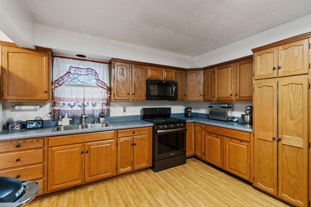 kitchen with sink, light hardwood / wood-style flooring, a textured ceiling, and black gas range