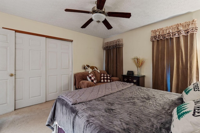 carpeted bedroom with ceiling fan, a closet, and a textured ceiling