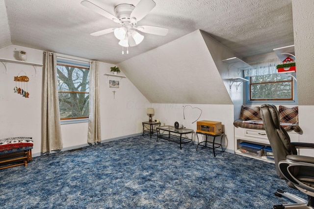 additional living space featuring lofted ceiling, ceiling fan, dark carpet, and a textured ceiling