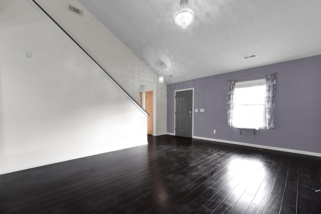 spare room featuring dark hardwood / wood-style flooring and a textured ceiling