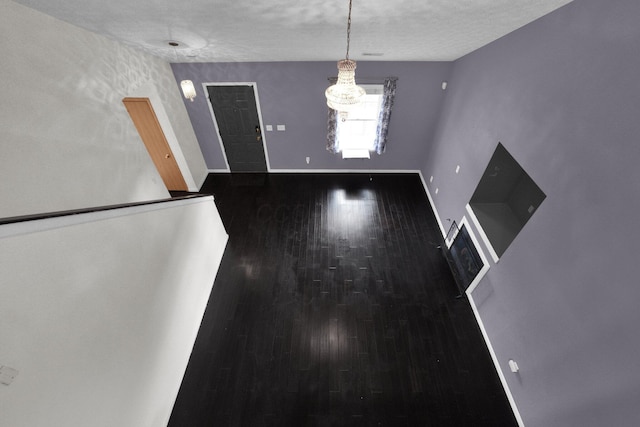 unfurnished dining area featuring dark hardwood / wood-style flooring and a textured ceiling