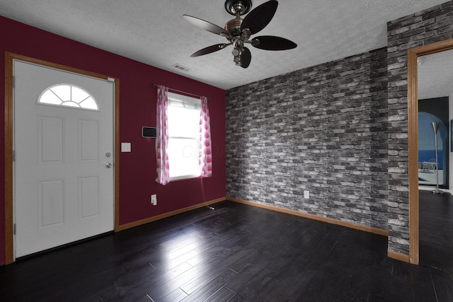 entryway with ceiling fan, brick wall, dark hardwood / wood-style flooring, and a textured ceiling