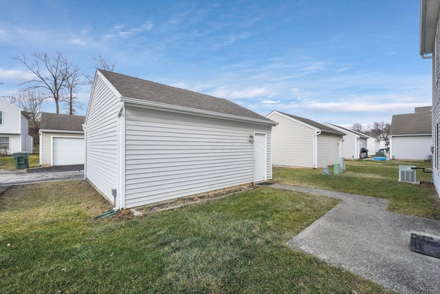 view of side of home featuring a garage, an outbuilding, central AC, and a lawn