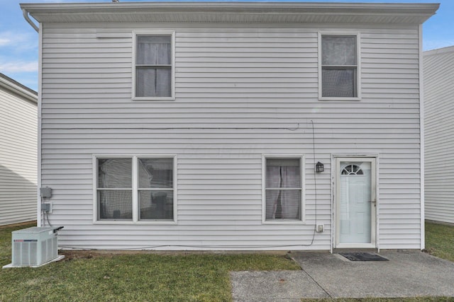 rear view of house featuring cooling unit and a yard