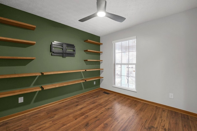 spare room featuring visible vents, a ceiling fan, a textured ceiling, wood finished floors, and baseboards