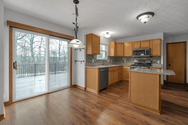 kitchen with dark wood-type flooring, a kitchen island, a sink, appliances with stainless steel finishes, and decorative backsplash